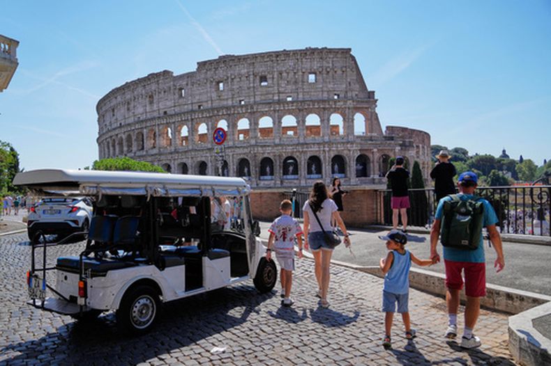 Un carrito de golf cerca del Coliseo, mientras varios turistas recorren las calles circundantes, en Roma, el martes 18 de agosto de 2026, destacando la creciente presencia de esos vehículos en el centro histórico de la capital mientras las autoridades actúan para frenar una industria a la que sus críticos culpan de empeorar la congestión, estacionarse ilegalmente y fomentar la saturación turística. (AP Foto/Gregorio Borgia)