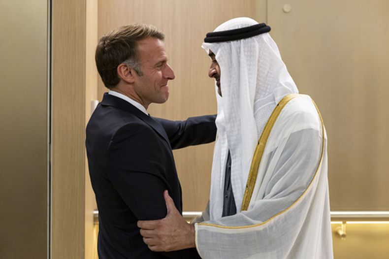 En esta fotografía publicada por la agencia estatal de noticias WAM, el jeque de Emiratos Árabes Unidos, Mohammed bin Zayed Al Nahyan, a la derecha, saluda al presidente de Francia, Emmanuel Macron, a su llegada a Abu Dabi, en Emiratos Árabes Unidos, el lunes 19 de octubre de 2026. (WAM via AP)