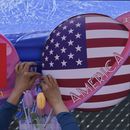 Un comerciante ata unas flores decoragivas entre dos banderas de China y Estados Unidos con forma de planeta, en una tienda durante el Carnaval de Primavera en Beijing, el 13 de mayo de 2023. (AP Foto/Andy Wong)