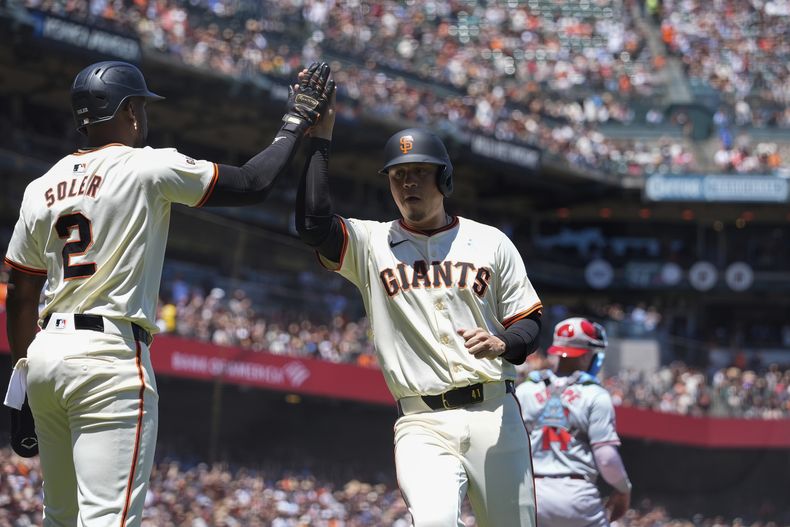 Jorge Soler, izquierda, y Wilmer Flores, de los Gigantes de San Francisco, celebran después de anotar carrera en contra de los Angelinos de Los Ángeles con doble de Thairo Estrada durante la cuarta entrada del juego de béisbol del domingo 16 de junio de 2024, en San Francisco. (AP Foto/Godofredo A. Vásquez)