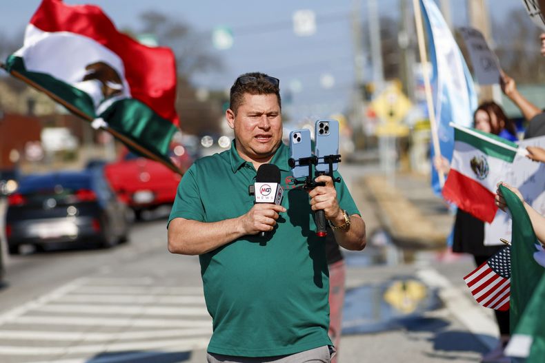 Mario Guevara, reportero de habla hispana del área metropolitana de Atlanta, cubre una protesta contra la aplicación de las leyes de inmigración, el sábado 1 de febrero de 2025, en la autopista Buford, Georgia. (Miguel Martinez/Atlanta Journal-Constitution vía AP)