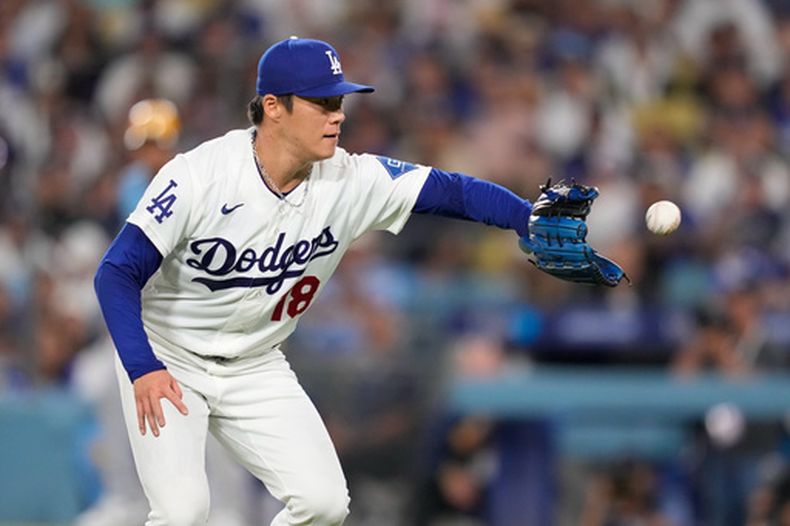 El japonés Yoshinobu Yamamoto, de los Dodgers de Los Ángeles, fildea una pelota en el juego ante los Cerveceros de Milwaukee, el viernes 14 de agosto de 2026 (AP Foto/Mark J. Terrill)