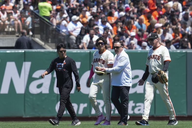 El jardinero central de los Gigantes de San Francisco, Jung Hoo Lee, segundo desde la izquierda, es asistido para salir del campo después de sufrir una lesión durante la primera entrada del juego de béisbol en contra de los Rojos de Cincinnati, el domingo 12 de mayo de 2024, en San Francisco. (AP Foto/Godofredo A. Vásquez)