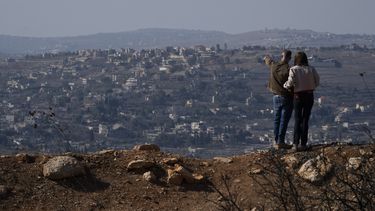 Una pareja israelí ve edificios en el sur del Líbano que han sido dañados en la guerra, desde el norte de Israel, el 30 de noviembre del 2024. (AP foto/Leo Correa)