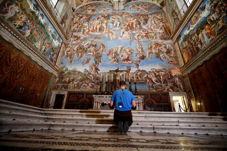 Un visitante se arrodilla frente al fresco del Juicio Final, obra del pintor italiano Miguel Ángel, dentro de la Capilla Sixtina, el 3 de mayo de 2021, en Roma. (AP Foto/Alessandra Tarantino, Archivo)