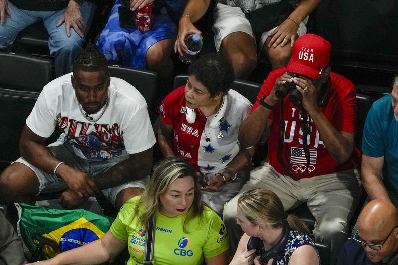 El esposo de Simone Biles, Jonathon Owens, junto a su madre y su padre, Ron y Nellie Biles, esperan el comienzo de la final de equipos femeninos de gimnasia artística en los Juegos Olímpicos de verano de 2024, el martes 30 de julio de 2024, en París, Francia. (Foto AP/Morry Gash)