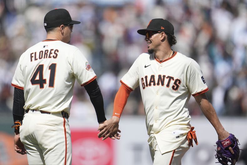 Wilmer Flores (41), de los Gigantes de San Francisco, celebra con Willy Adames después de un juego de béisbol contra los Rockies de Colorado en San Francisco, el domingo 4 de mayo de 2025. (AP Foto/Jeff Chiu)