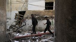Palestinos caminan junto a un edificio dañado tras una operación del ejército israelí en el campo de refugiados de Yenín, Cisjordania, el domingo 26 de noviembre de 2023. (AP Foto/Majdi Mohammed)