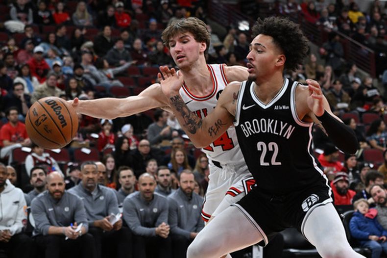 Jalen Wilson (22), de los Nets de Brooklyn, lucha contra Matas Buzelis (14), de los Toros de Chicago, por un balón suelto durante la primera mitad de un juego de baloncesto de la NBA en Chicago, el domingo 18 de enero de 2026. (AP Photo/Paul Beaty)