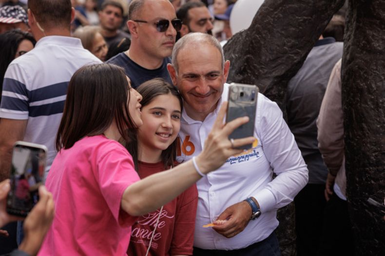 El primer ministro de Armenia, Nikol Pashinyan, posa para una selfi con una partidaria mientras camina por la avenida Norte de Ereván, Armenia, el lunes 1 de junio de 2026, durante celebraciones públicas por el Día del Niño. (AP Foto/Anthony Pizzoferrato)