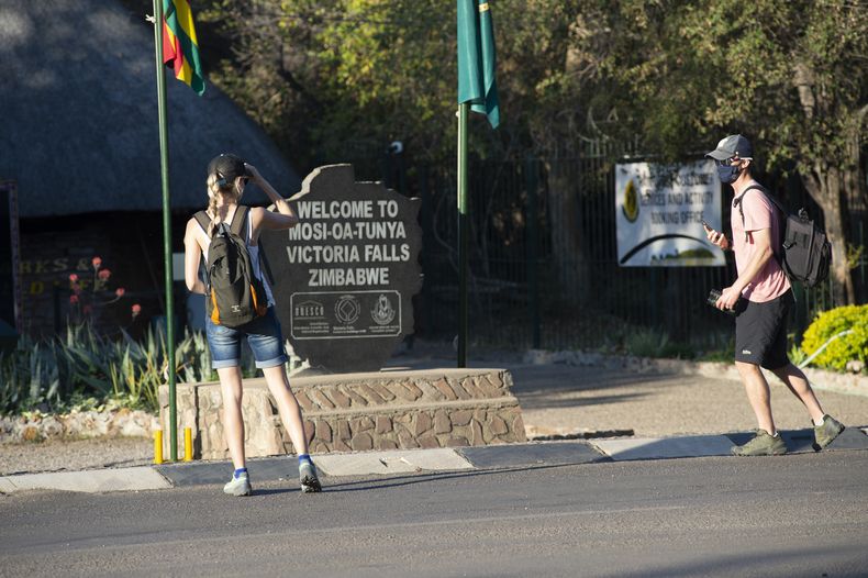 Turistas en la entrada de las Cataratas de Victoria en Zimbabue el 6 de agosto de 2021. (Foto AP /Tichaona Muketiwa)