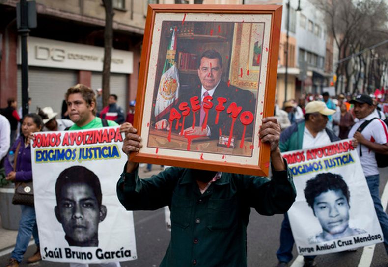 ARCHIVO - Un manifestante sostiene un retrato de Ángel Aguirre, exgobernador del estado de Guerrero, en el que se ha escrito la palabra asesino durante una marcha contra la desaparición de 43 estudiantes de una escuela rural de magisterio, el 26 de enero de 2015, en Ciudad de México. (Foto AP/Eduardo Verdugo, archivo)
