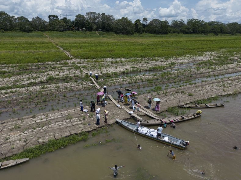 Miembros de la comunidad indígena ticuna recibe ayuda de una ONG ante la sequía que se registra a lo largo del río Amazonas en Santa Sofía, en las afueras de Leticia, Colombia, el domingo 20 de octubre de 2024. (AP Foto/Iván Valencia)