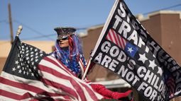 Micki Larson-Olson sostiene una bandera cerca del sitio donde el gobernador de Texas, Greg Abbott, y otros gobernadores republicanos se reunieron junto al río Bravo (o Grande) en la frontera entre Estados Unidos y México, el domingo 4 de febrero de 2024, en Eagle Pass, Texas. (AP Foto/Eric Gay)