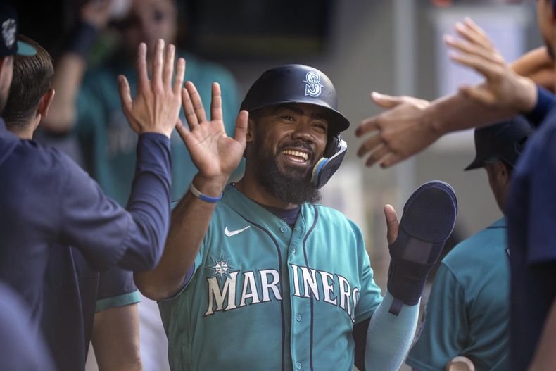 Teoscar Hernandez felicitado por sus compañeros de los Marineros de Seattle en el dugout tras anotar con el sencillo de Jarred Kelenic en el encuentro ante los Rays de Tampa Bay el sábado 1 de julio del 2023. (AP Foto/Stephen Brashear)