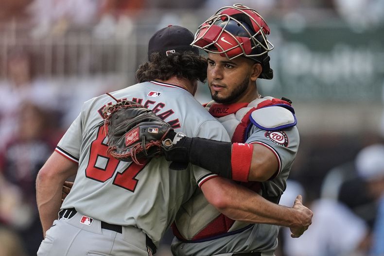 Kyle Finnegan (67), de los Nacionales de Washington, abraza al receptor Keibert Ruiz (20) después de un partido de béisbol contra los Bravos de Atlanta, el lunes 27 de mayo de 2024, en Atlanta. (AP Foto/Mike Stewart)