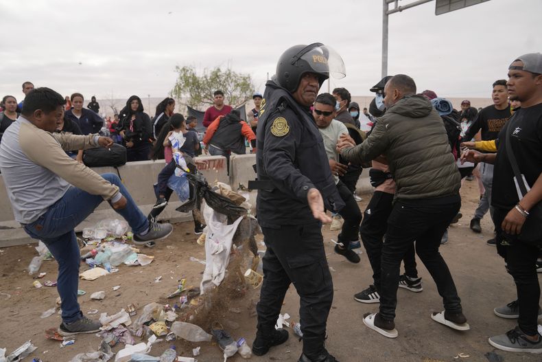 Un ciudadano peruano, a la izquierda, pelea con migrantes venezolanos en la frontera peruana con Chile, en Tacna, Perú, el sábado 29 de abril de 2023. Una crisis migratoria en la frontera entre Chile y Perú se ha intensificado desde el jueves, ya que cientos de migrantes quedaron varados tras no poder cruzar a Perú. (Foto AP/Martín Mejía)