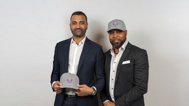 En esta foto suministrada por Baseball United, el ex Grandes Ligas Barry Larkin (derecha), codueño de Baseball United, y Kash Shaik, CEO y codueño de Baseball United, posan con los gorros de Mumbai Cobras en la presentación de la franquicia en Cincinnati, Ohio, el viernes 5 de mayo de 2023. (Baseball United, Inc. vía AP)