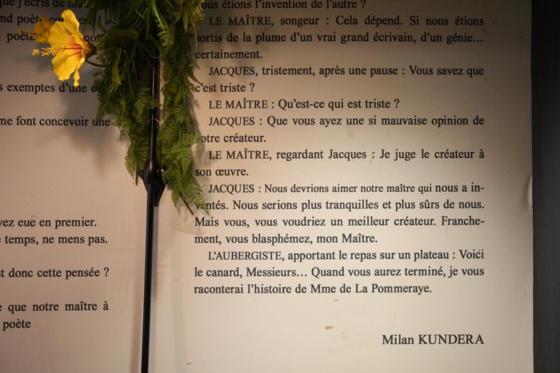 Una flor colocada permanentemente junto a un extracto de la obra de teatro de Milan Kundera Jacques et son Maitre en un restaurante cerca de su casa en París, el miércoles 12 de julio de 2023. Milan Kundera, cuyos escritos disidentes en la Checoslovaquia comunista lo transformaron en un exiliado satírico del totalitarismo, ha muerto en París. Tenía 94 años. (Foto AP/Christophe Ena)