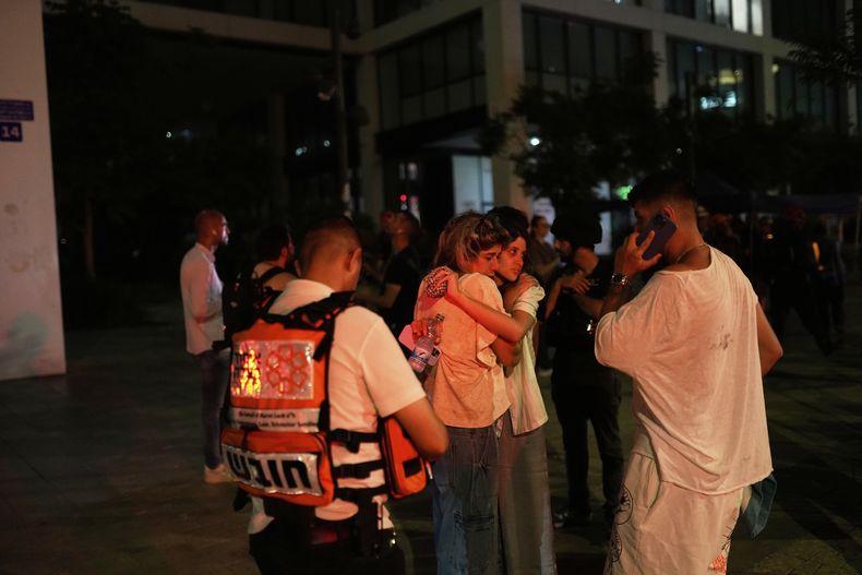 Varias personas aguardan y se apoyan mutuamente junto a un edificio alcanzado por un misil disparado desde Irán, el viernes 13 de junio de 2025, en Tel Aviv, Israel. (AP Foto/Tomer Appelbaum)
