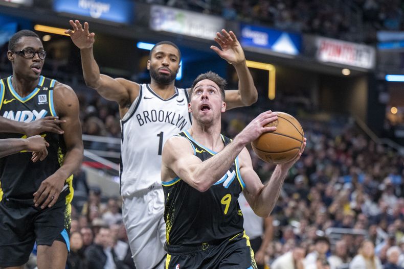 El escolta de los Pacers de Indiana, T.J. McConnell (9), dispara después de esquivar la defensa del alero de los Nets de Brooklyn, Mikal Bridges (1), durante la segunda mitad del partido de baloncesto de la NBA en Indianápolis, el sábado 16 de marzo de 2024. (AP Foto/Doug McSchooler)