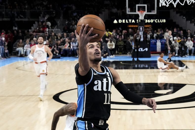 Trae Young (11), de los Hawks de Atlanta, anota una bandeja en contra de los Spurs de San Antonio durante la primera mitad del juego de baloncesto de la NBA, el lunes 15 de enero de 2024, en Atlanta. (AP Foto/John Bazemore)
