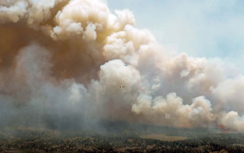 En esta imagen aérea, una aeronave, centro, sobrevuela un incendio cerca del Lago Lake en el condado Shelburne, en Canadá, el miércoles 31 de mayo de 2023. (Communications Nova Scotia/The Canadian Press via AP)