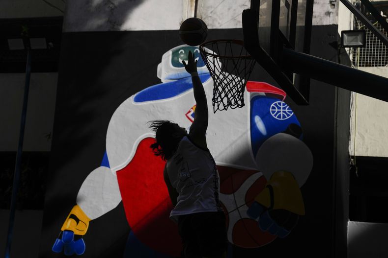 Un individuo juega basquetbol frente a un muro pintada con la mascota de la Copa Mundial de basquetbol, el jueves 17 de agosto de 2023, en Taguig, Filipinas. (AP Foto/Aaron Favila)