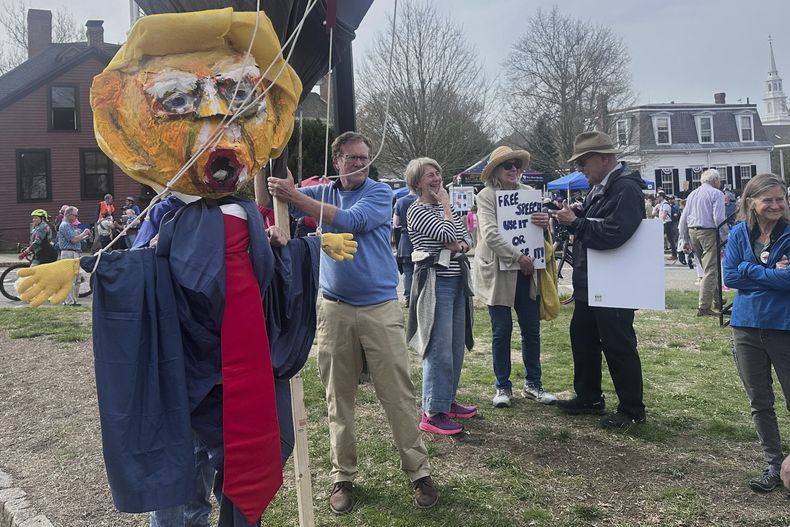 Un grupo de manifestantes caminan detrás de un desfile para conmemorar el 250mo aniversario de la Guerra de Independencia de Estados Unidos, el sábado 19 de abril de 2025, en Concord, Massachusetts. (AP Fotos/Michael Casey)