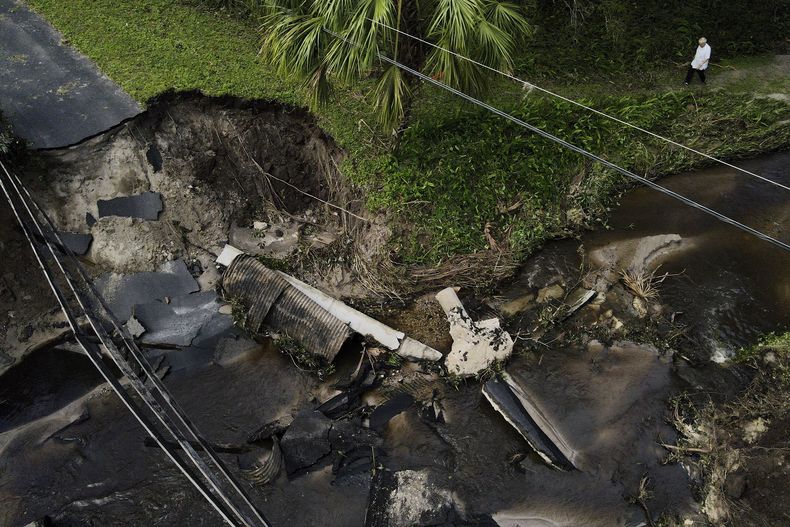 Del Ockey, un canadiense que vive en Florida durante los seis meses más fríos del año, camina cerca de un puente dañado que va hacia su propiedad, en Riverview, Florida, el viernes 11 de octubre de 2024, tras el paso del huracán Milton. (AP Foto/Julio Cortez)