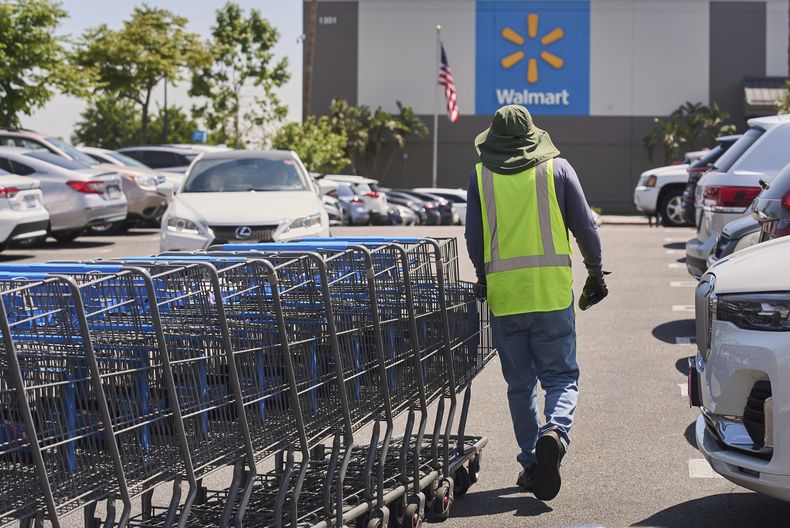 ARCHIVO - Un empleado recolecta carritos para compras vacíos del estacionamiento de una tienda de la cadena Walmart en Burbank, California, el jueves 10 de abril de 2025. (AP Foto/Damian Dovarganes, archivo)