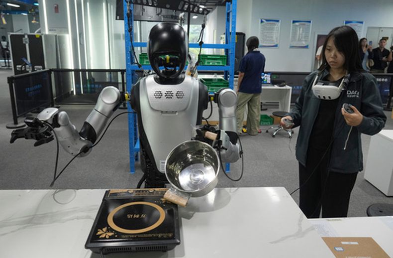 Una trabajadora controla a distancia a robots humanoides durante los preparativos para la Feria Internacional China de Comercio en Servicios (CIFTIS) en un centro de entrenamiento de robots en Beijing, China, el lunes 10 de agosto de 2026. (AP Foto/Achmad Ibrahim)