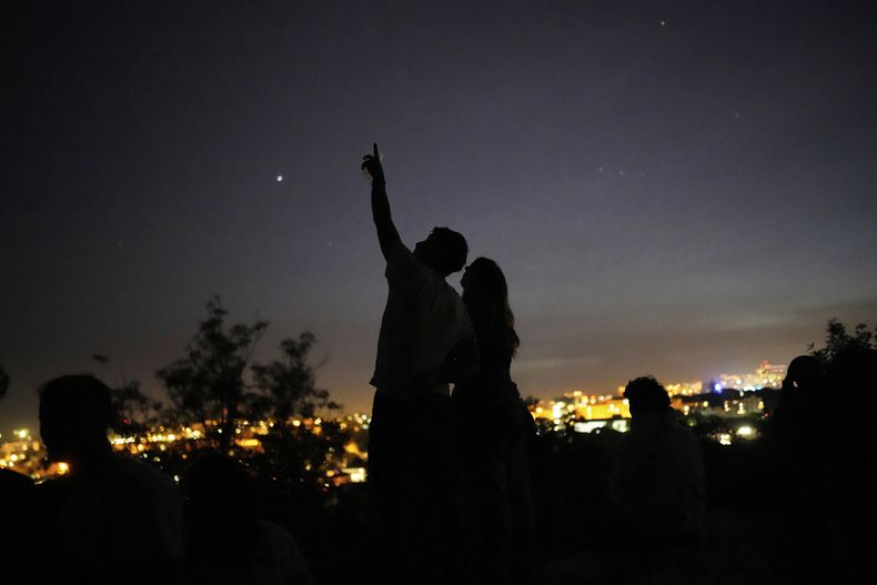 Una joven pareja observa el cielo desde un mirador de Lisboa durante un apagón nacional, el lunes 28 de abril de 2025. (AP foto/Armando Franca)