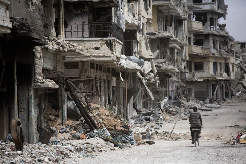Un hombre recorre en su bicicleta una calle devastada en Homs, Siria, el 5 de junio de 2014. (Foto AP/Dusan Vranic)