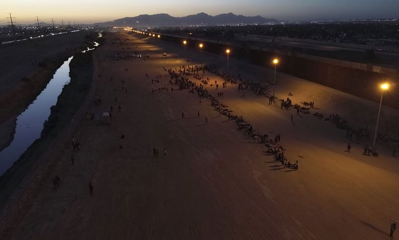 Migrantes esperan a las autoridades estadounidenses, entre una barrera de alambre de púas y la valla fronteriza en la frontera entre Estados Unidos y México, el miércoles 10 de mayo de 2023, en Ciudad Juárez, México. Un gran número de solicitantes de asilo llegaron a la frontera entre ambos países días antes de la expiración del Título 42, que le había permitido al gobierno estadounidense expulsar rápidamente a los migrantes a México. El miércoles se anunciaron nuevas medidas que crean nuevas vías legales para los migrantes. En redes sociales la desinformación al respecto ha circulado ampliamente. (Foto AP/Christian Chávez)