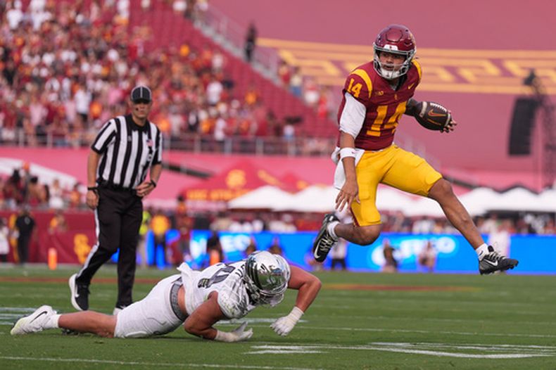 El quarterback de los Trojans de Southern California, Jayden Maiava (derecha), evade al apoyador de los Ducks de Oregon, Teitum Tuioti, durante la primera mitad de un partido de fútbol americano universitario, el 26 de septiembre de 2026, en Los Ángeles. (Foto AP/Mark J. Terrill)