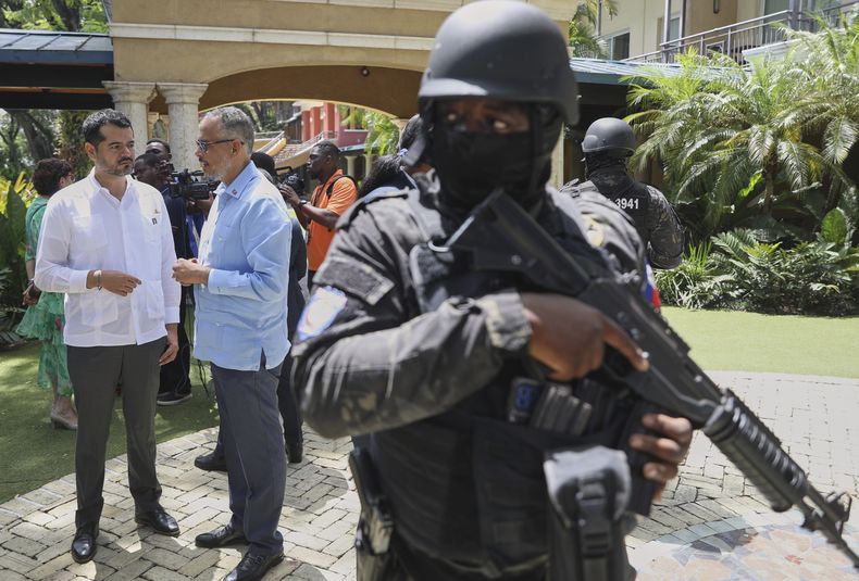 Guardias de seguridad observan mientras el primer ministro de Haití, Alix Didier Fils-Aime, en el centro, conversa con el encargado de negocios de México, Jesús Cisneros, en Puerto Príncipe, Haití, el jueves 26 de junio de 2025. (AP Foto/Odelyn Joseph)