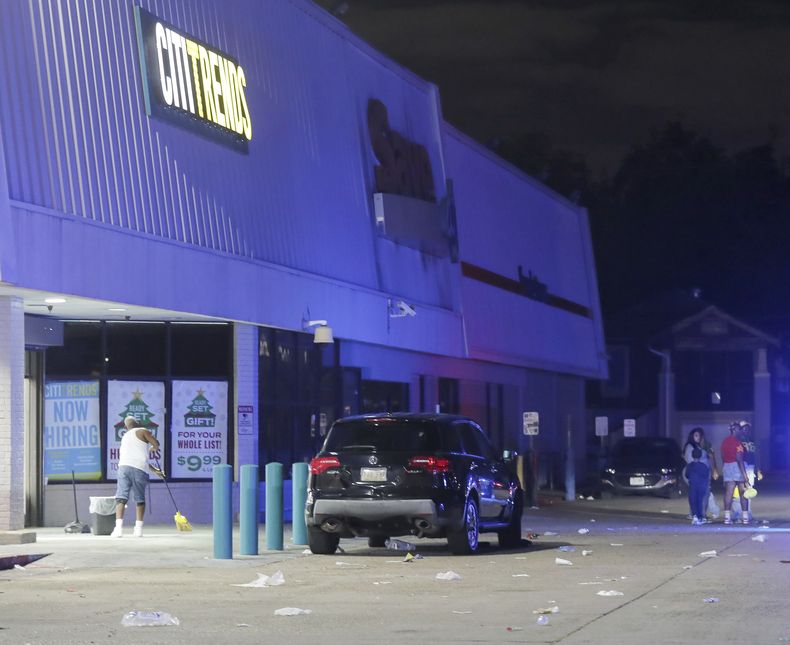 Un empleado de Cititrends realiza tareas de limpieza en un estacionamiento de una tienda de la cadena Save O Lot donde varias personas fueron baleadas en un tiroteo mortal en Nueva Orleans, el domingo 17 de noviembre de 2024. (David Grunfeld/The Times-Picayune/The New Orleans Advocate vía AP)