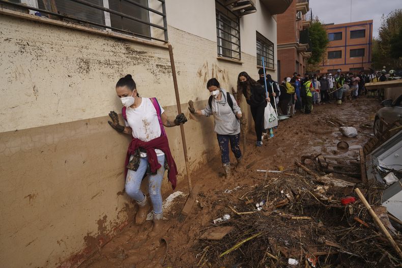 Voluntarios caminan entre el lodo para colaborar en las tareas de limpieza tras las inundaciones que arrasaron Massanassa, a las afueras de Valencia, el 2 de noviembre de 2024. (AP Foto/Alberto Saiz)