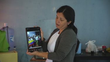 La venezolana Betania Rodríguez muestra con su tableta una foto grupal con el papa León XIV y el entonces obispo Robert Prevost en un albergue para migrantes administrado por Prevost y la Orden de San Vicente de Paúl en Chiclayo, Perú, el sábado 10 de mayo de 2025. (Foto AP/Guadalupe Pardo)