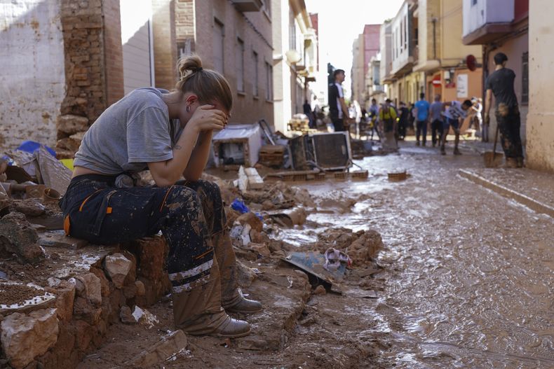 Una mujer descansa mientras residentes y voluntarios limpian una zona arrasada por las inundaciones en Paiporta, cerca de Valencia, España, el 1 de noviembre de 2024. (AP Foto/Alberto Saiz)