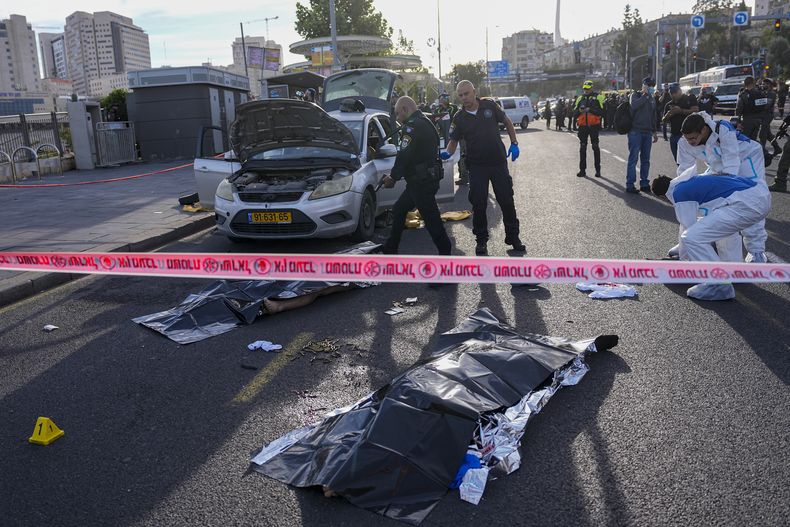 Un agente de policía israelí apunta su arma al cuerpo de un hombre implicado en un ataque en Jerusalén, el jueves 30 de noviembre de 2023. Dos hombres dispararon contra la gente en una estación de autobús en la entrada de Jerusalén, donde dejaron varios muertos y heridos, según la policía. (AP Foto/Ohad Zwigenberg)