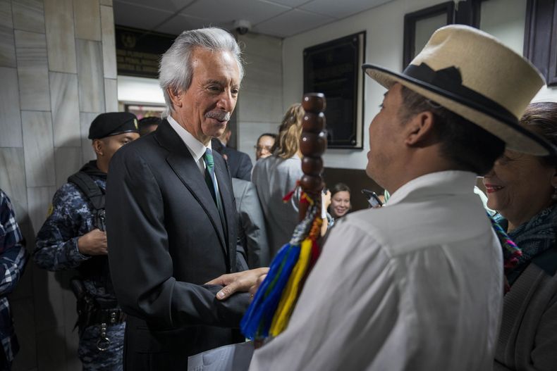 El líder indígena maya achi Pedro González, a la derecha, saluda al periodista detenido José Rubén Zamora, quien llega a la corte para un nuevo juicio en la ciudad de Guatemala, el miércoles 21 de febrero de 2024. Zamora, fundador del diario cerrado El Periódico de Guatemala, fue sentenciado a seis años de prisión en 2023 por lavado de dinero, pero un tribunal superior anuló esa decisión y ordenó un nuevo juicio. (AP Foto/Moisés Castillo)