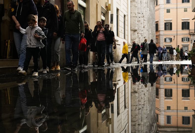 Personas cruzan un charco después de fuertes lluvias en el centro de Roma, el martes 2 de mayo de 2023. (Foto AP/Alessandra Tarantino)