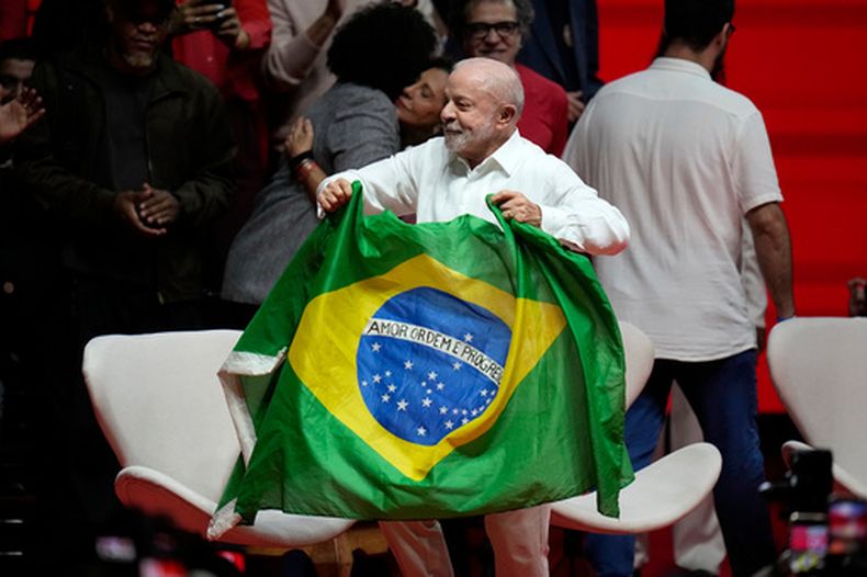 El presidente brasileño Luiz Inácio Lula da Silva llega con una bandera brasileña a un mitin de campaña con artistas en Río de Janeiro, Brasil, el miércoles 23 de septiembre de 2026. (AP Foto/Silvia Izquierdo)