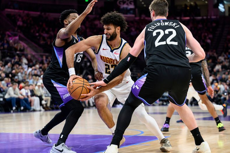 Jamal Murray, centro, de los Nuggets de Denver, se enfila hacia la canasta entre Elijah Harkless, izquierda, y Kyle Filipowski, derecha, del Jazz de Utah, durante la segunda mitad del juego de baloncesto de la NBA, el lunes 2 de marzo de 2026, en Salt Lake City. (AP Foto/Tyler Tate)