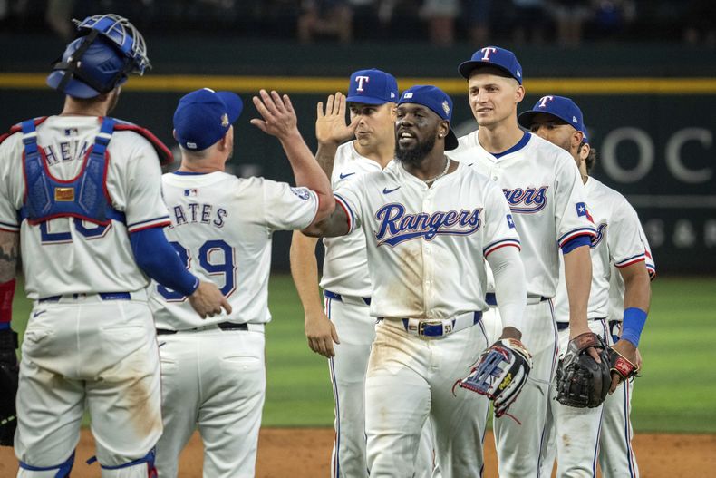 Adolis García, centro, de los Rangers de Texas, y Corey Seager, a la derecha, celebran con Kirby Yates (39) y Jonah Heim, a la izquierda, después de su victoria por 6-1 sobre los Diamondbacks de Arizona en el partido de béisbol el miércoles 29 de mayo de 2024, en Arlington, Texas. (AP Foto/Jeffrey McWhorter)