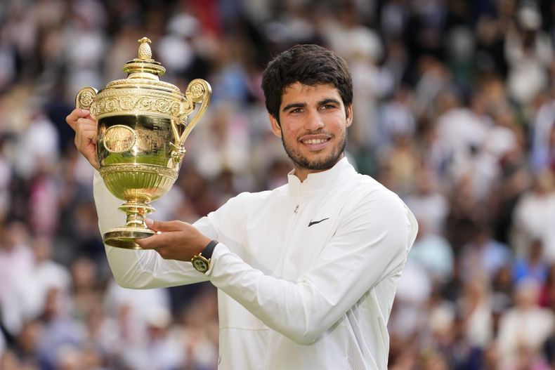 Carlos Alcaraz alza el trofeo de campeón de Wimbledon tras derrotar a Novak Djokovic en la final, el domingo 16 de julio de 2023, en Londres. (AP Foto/Kirsty Wigglesworth)
