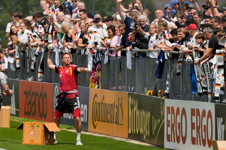 Julian Nagelsmann, el técnico de la selección de Alemania, lanza balones al público durante un entrenamiento en Fráncfort, el lunes 1 de junio de 2026. (AP Foto/Michael Probst)