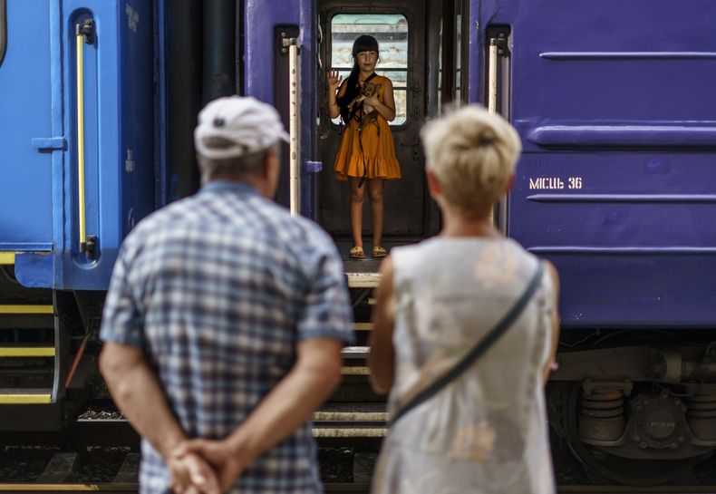 Una niña carga a su perro mientras se despide de sus abuelos parada en un tren de desalojo que sale de Pokrovsk, región de Donetsk, este de Ucrania, el martes 2 de agosto de 2022, hacia una zona más segura del país en el oeste. (AP Foto/David Goldman)